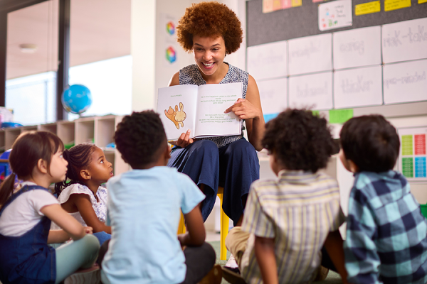 Woman smiling and reading to a group of children