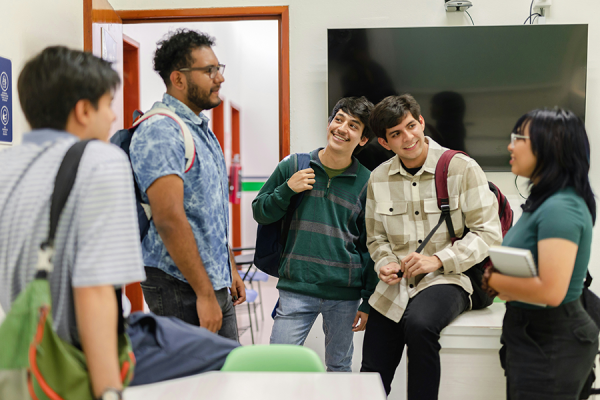 Group of five teens, four boys and a girl, standing in a room with backpacks