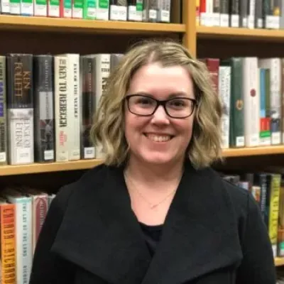 Andrea Dickson library director standing in front of bookcase