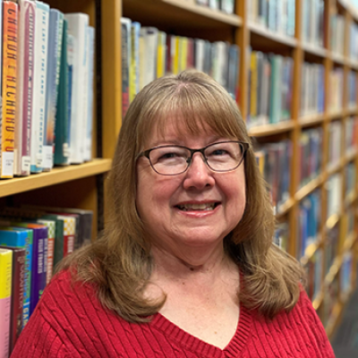 Carol Barone executive assistant standing in front of a bookcase