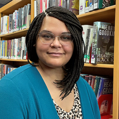 Melitta Floyd adult services librarian standing in front of a bookcase