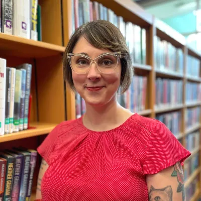 Sarah Sorensen teen & adult services librarian standing in front of a bookcase